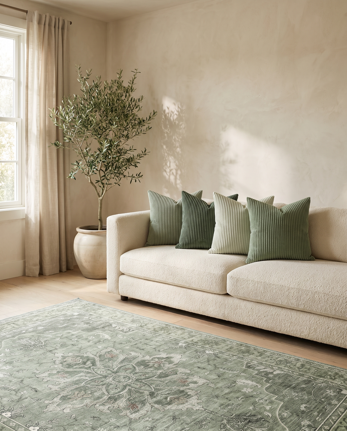 Sorrel sage pillows on a bouclé sofa with the Juniper rug — lifestyle
