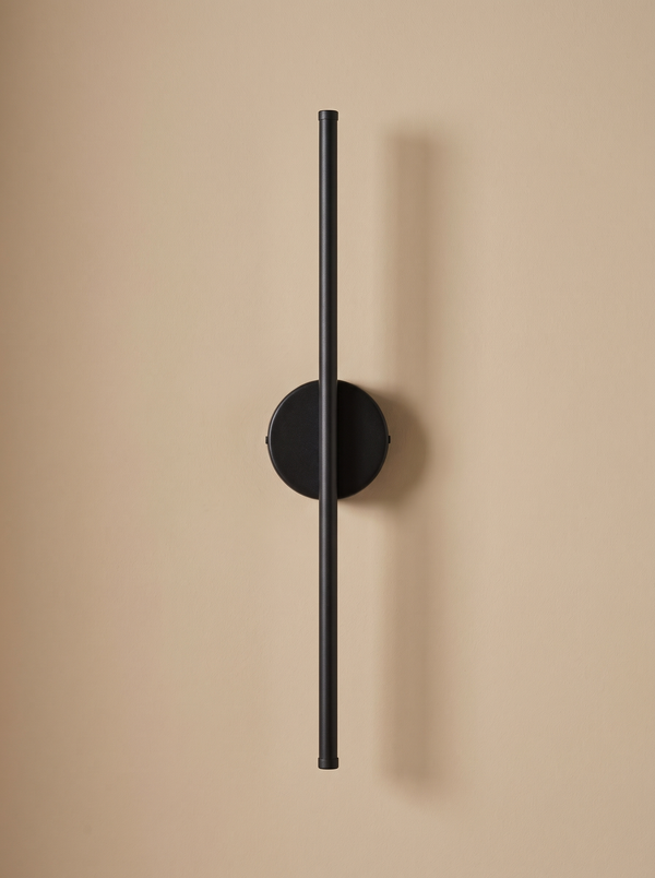 Tarn slim LED wall sconce in matte black on a warm sand backdrop