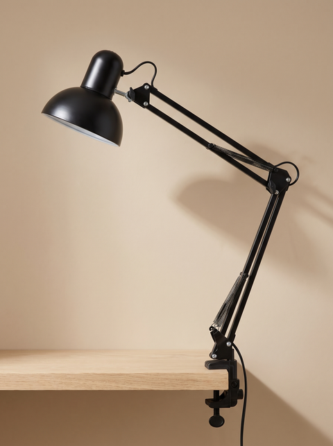 Otis architect clamp lamp in black on a warm sand backdrop