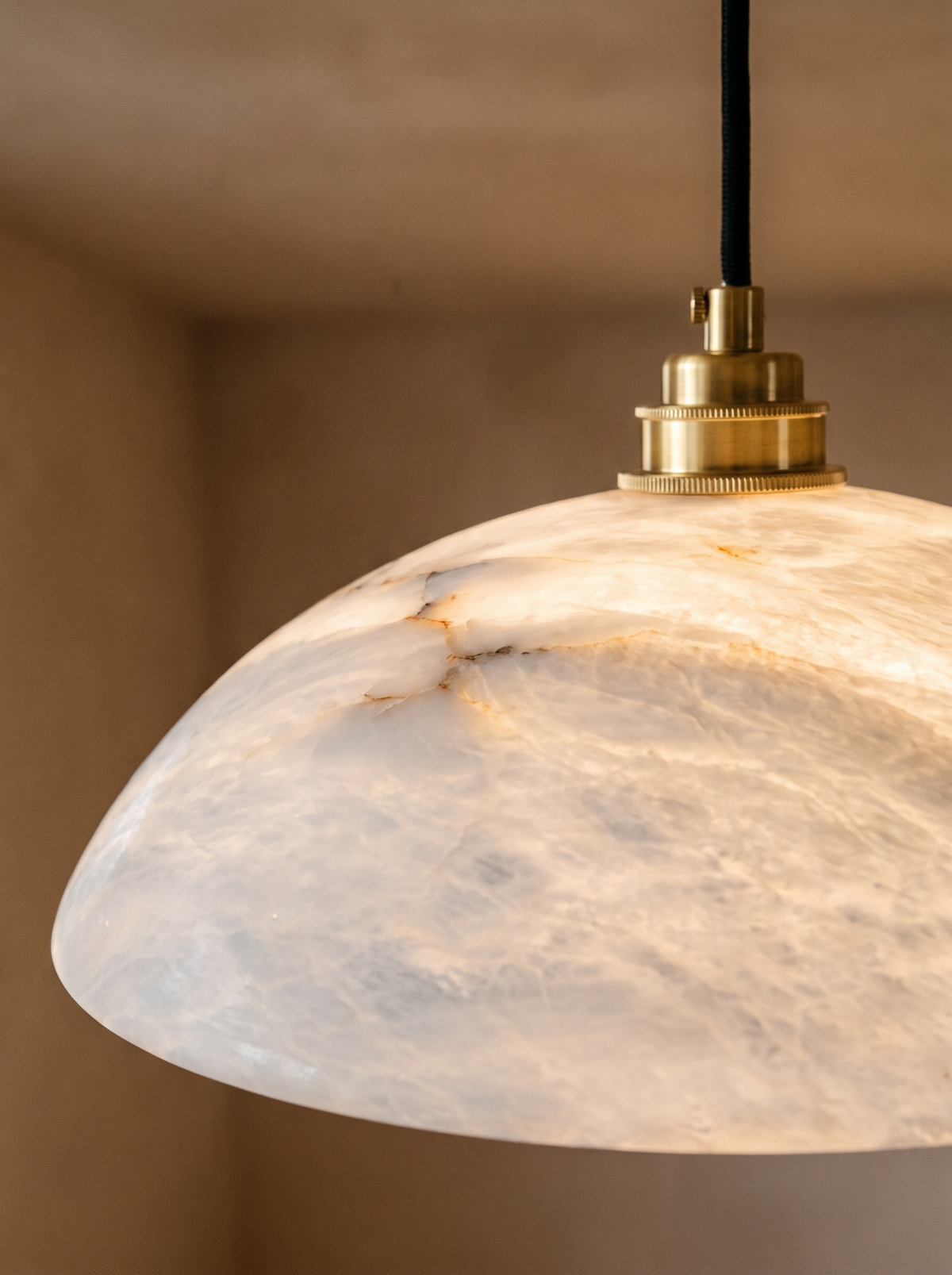 Lifestyle: close-up of Cala's veined alabaster dome and brass cap, lit