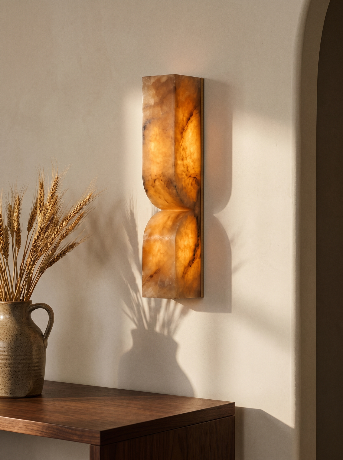 Aurelie carved alabaster wall sconce in gold and brown alabaster on a cream plaster wall
