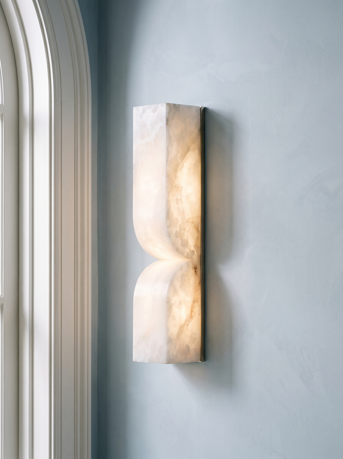 Aurelie carved alabaster wall sconce in nickel and white on a powder-blue plaster wall