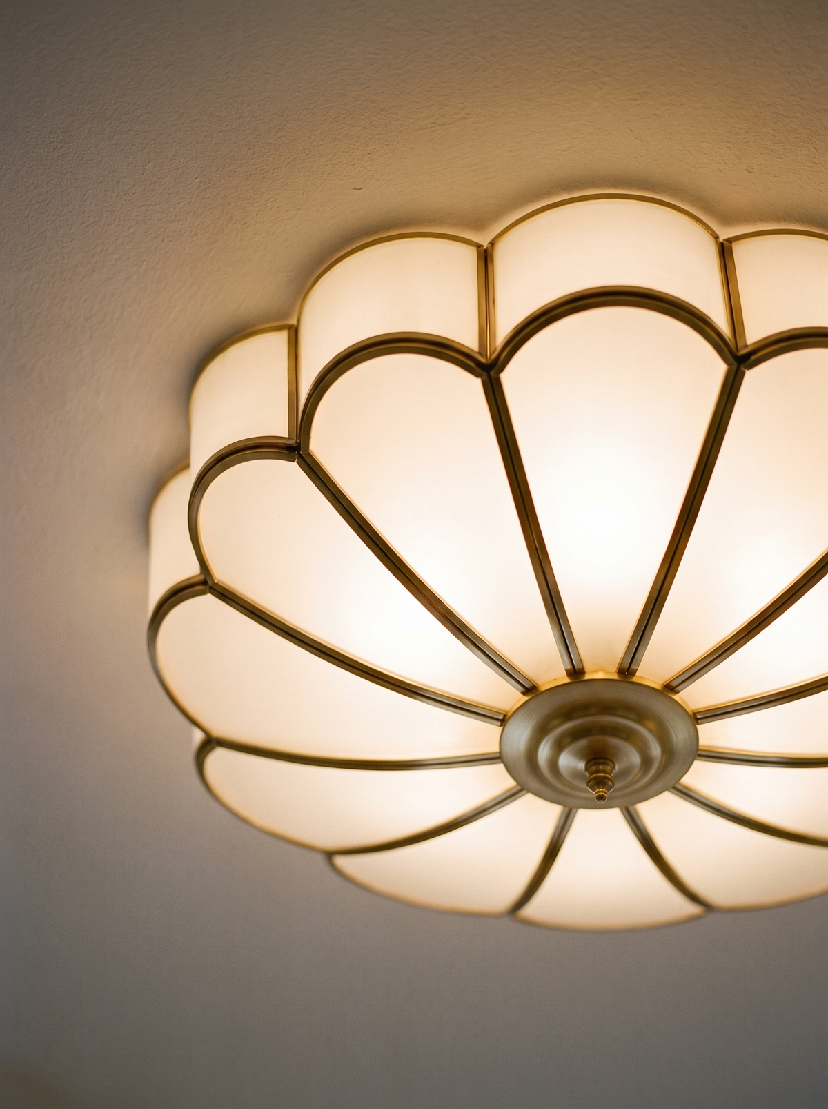 Lifestyle: close-up of Marguerite's frosted glass petals and brass frame, lit