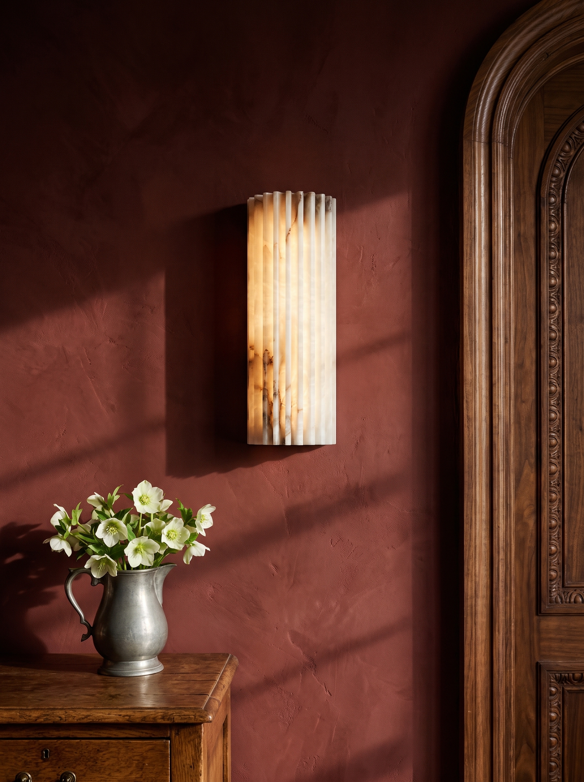 Clio ribbed alabaster wall sconce on an oxblood plaster wall