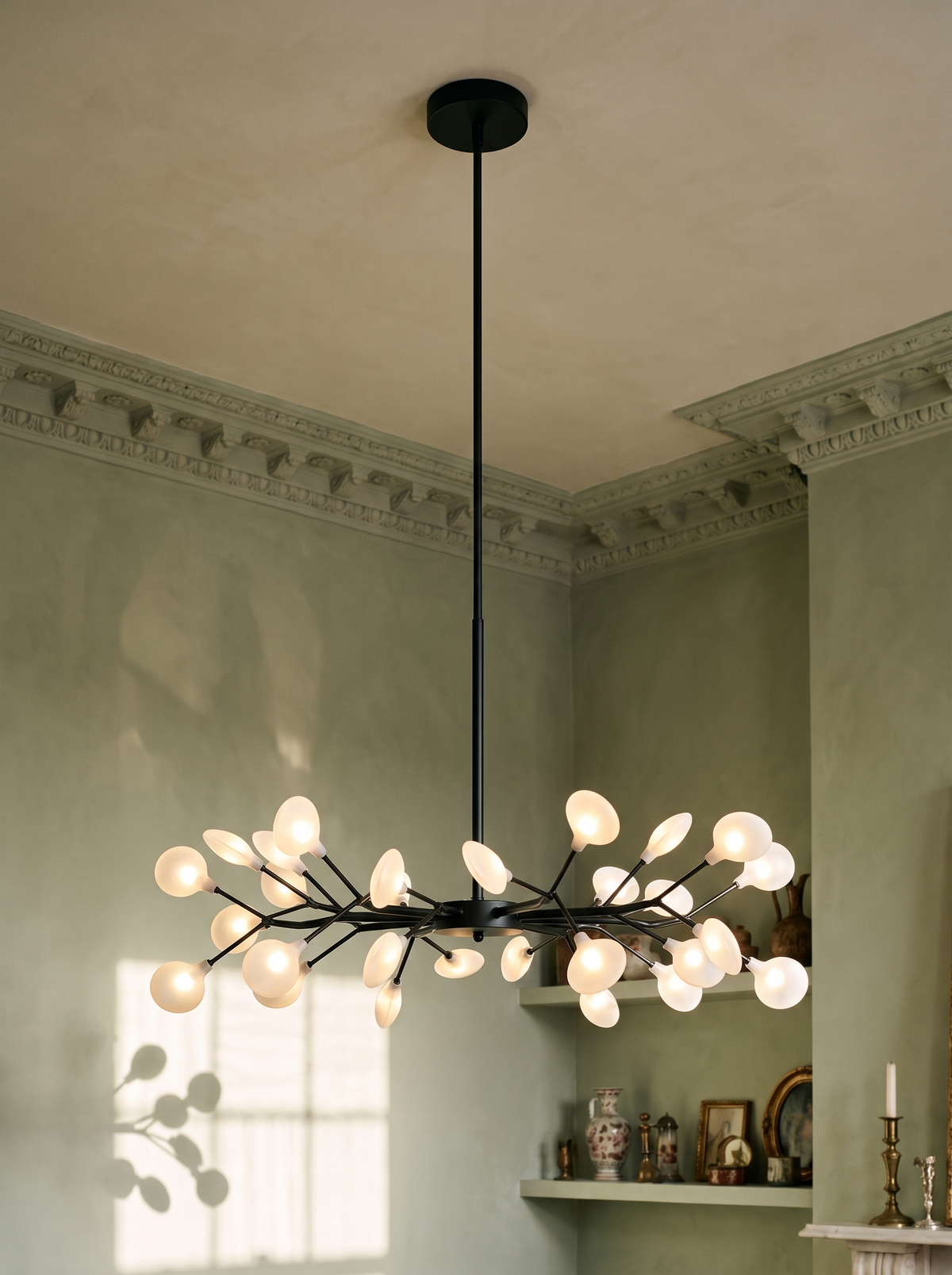 Luce firefly sputnik chandelier in black hanging in a sage plaster-moulded corner