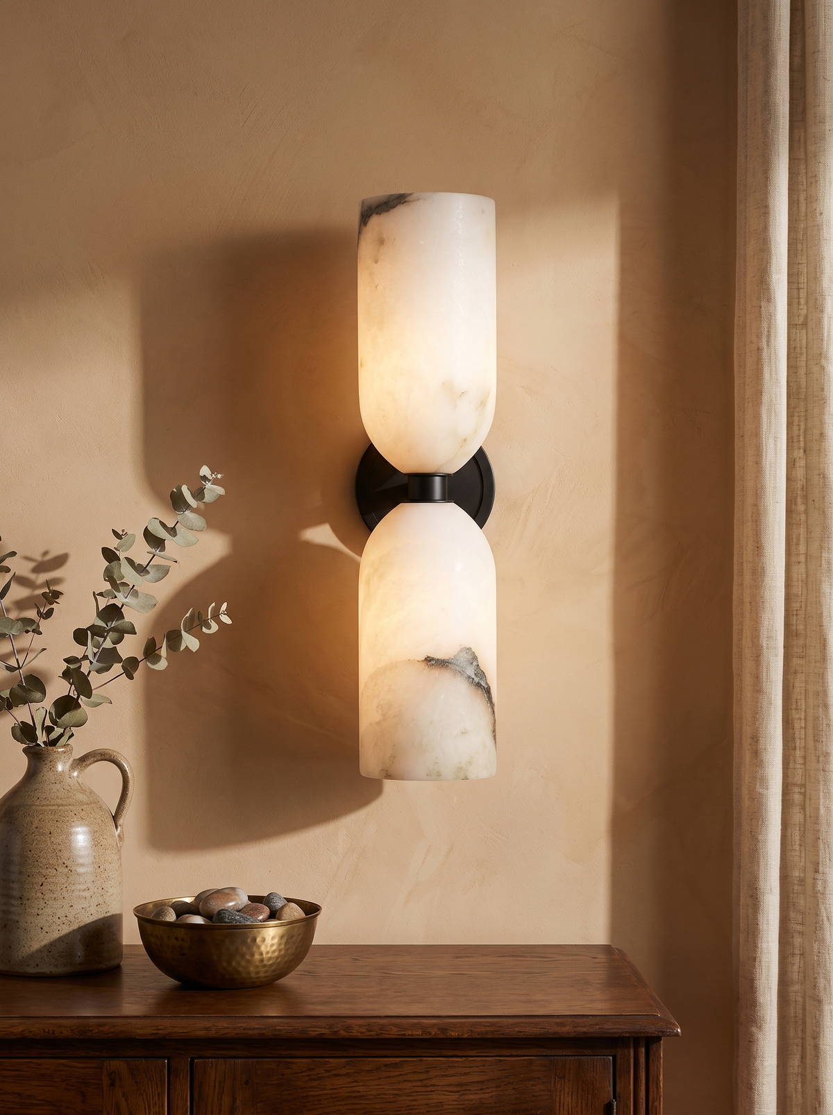 Nyx up-and-down alabaster wall sconce in black on a caramel plaster wall
