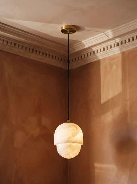 Oaklee acorn alabaster pendant light in brass hanging in a sienna plaster-moulded corner