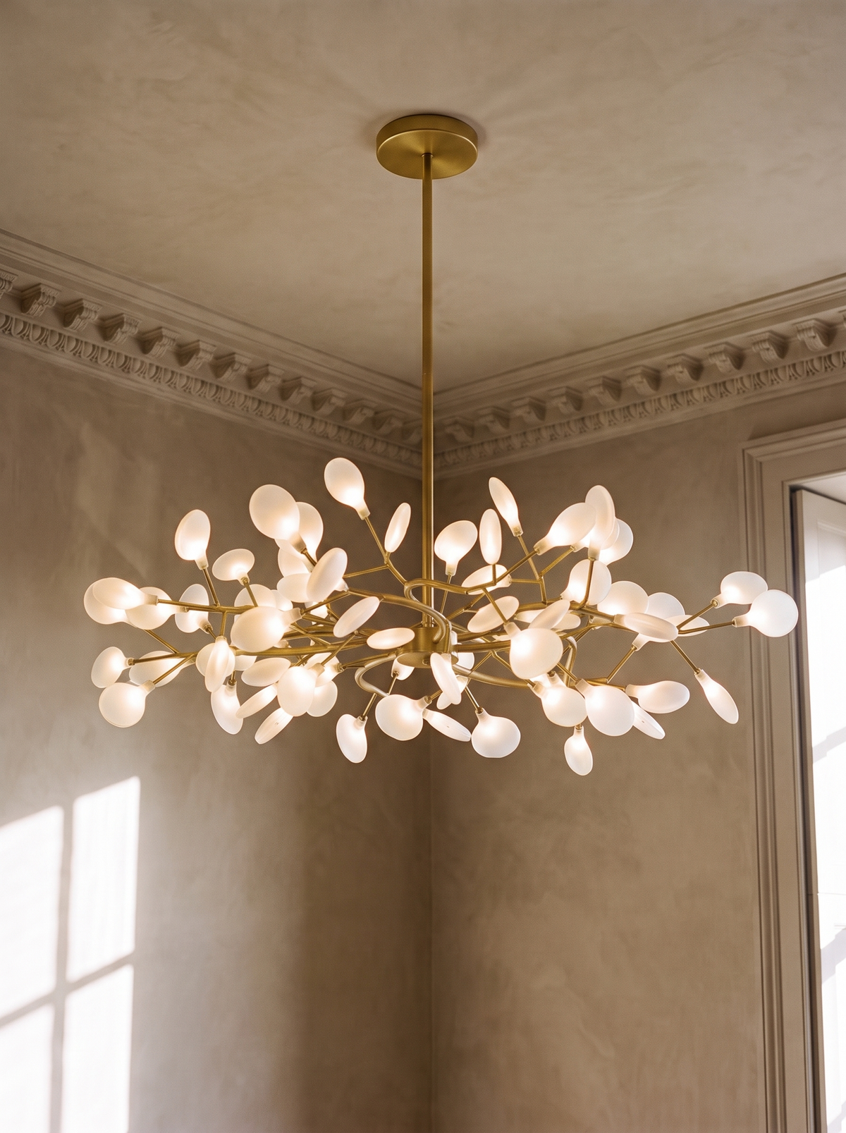 Luce 63-light firefly chandelier in gold hanging in a plaster-moulded corner
