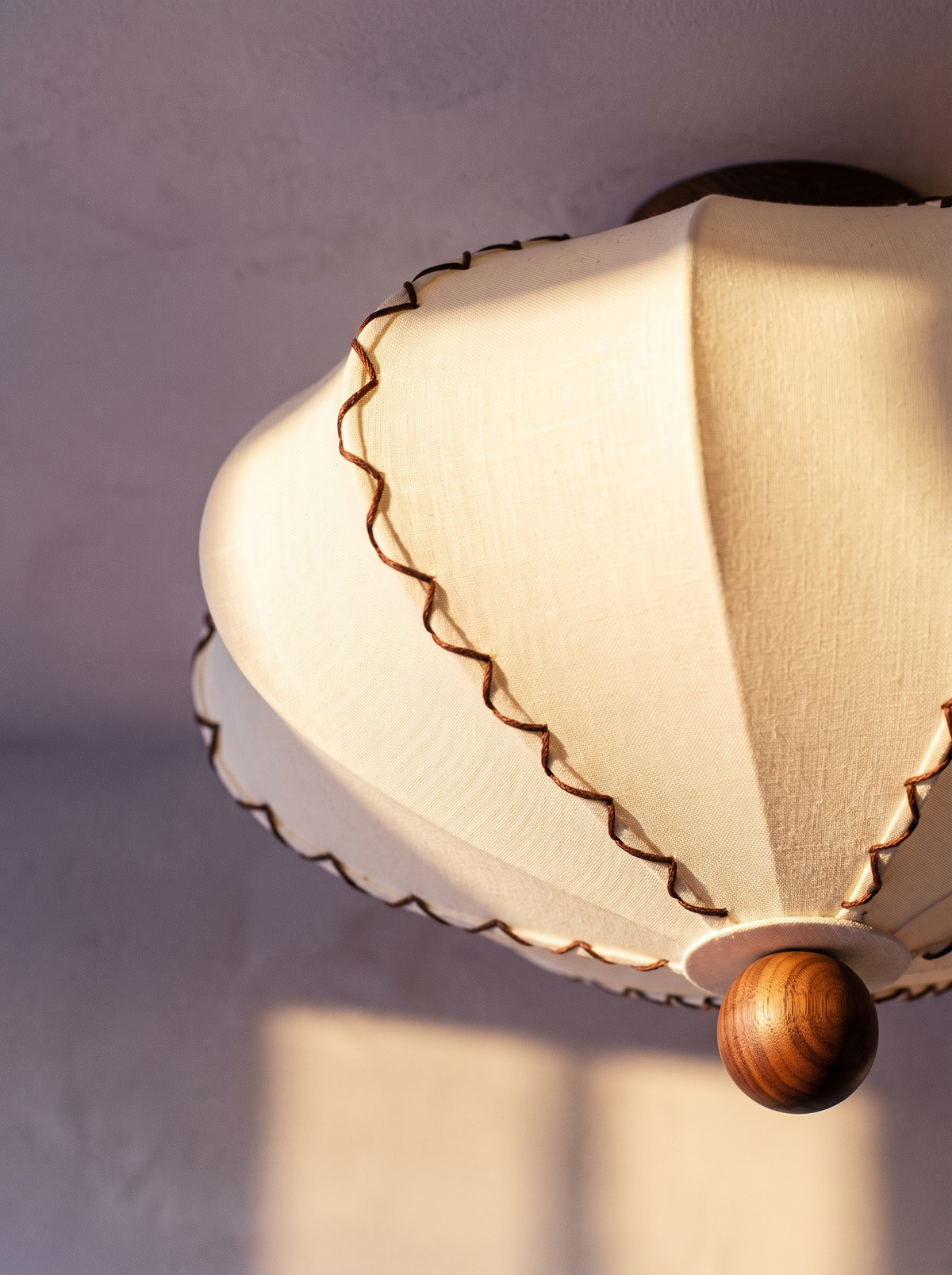 Lifestyle: close-up of Bonnie's scalloped fabric, contrast piping and walnut finial, lit