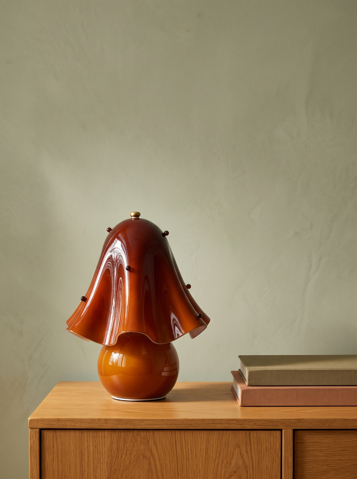Petal amber glass flower table lamp on an oak console against a warm plaster wall