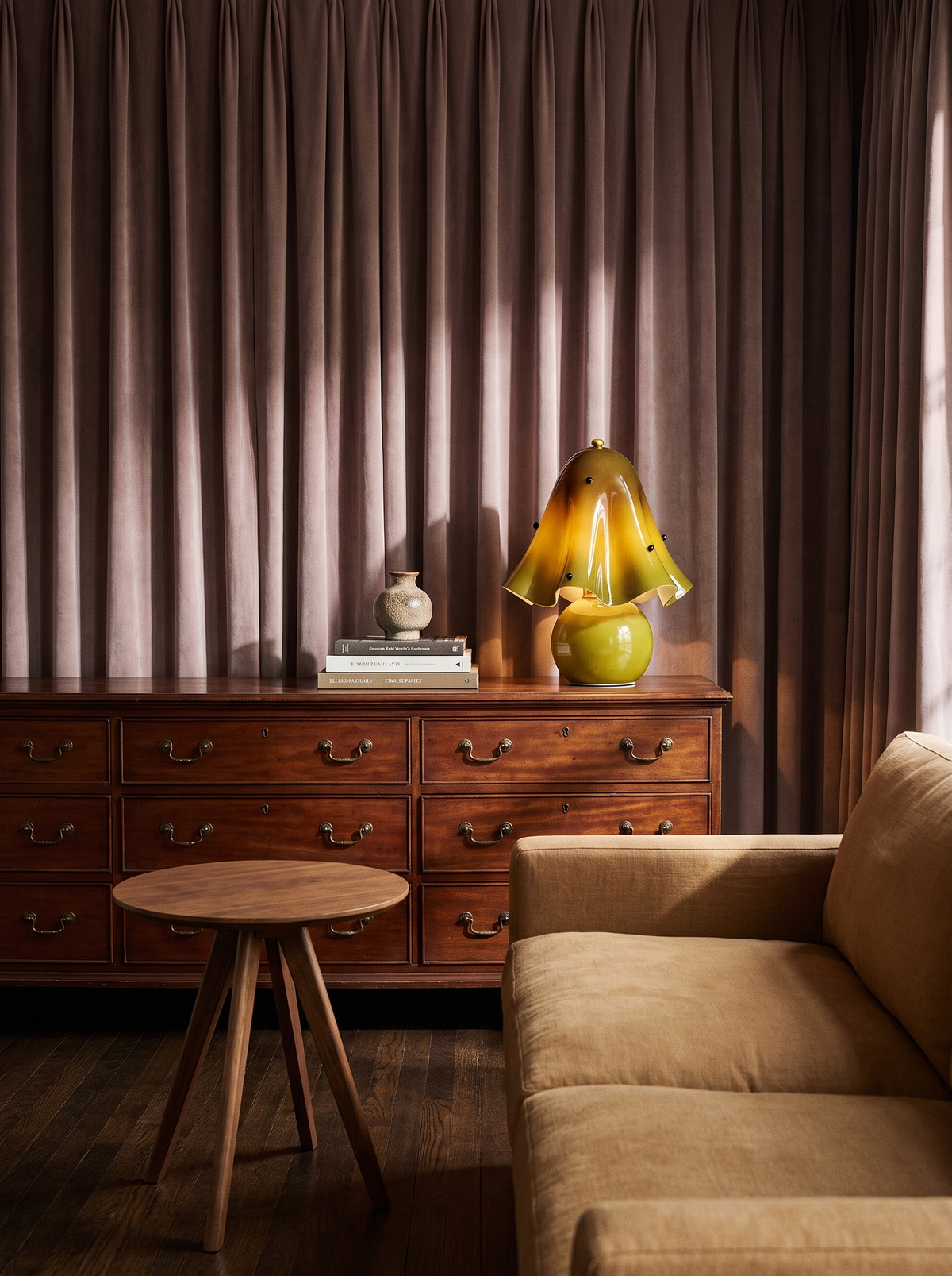 Lifestyle: Petal green glass table lamp on a mahogany chest by velvet curtains
