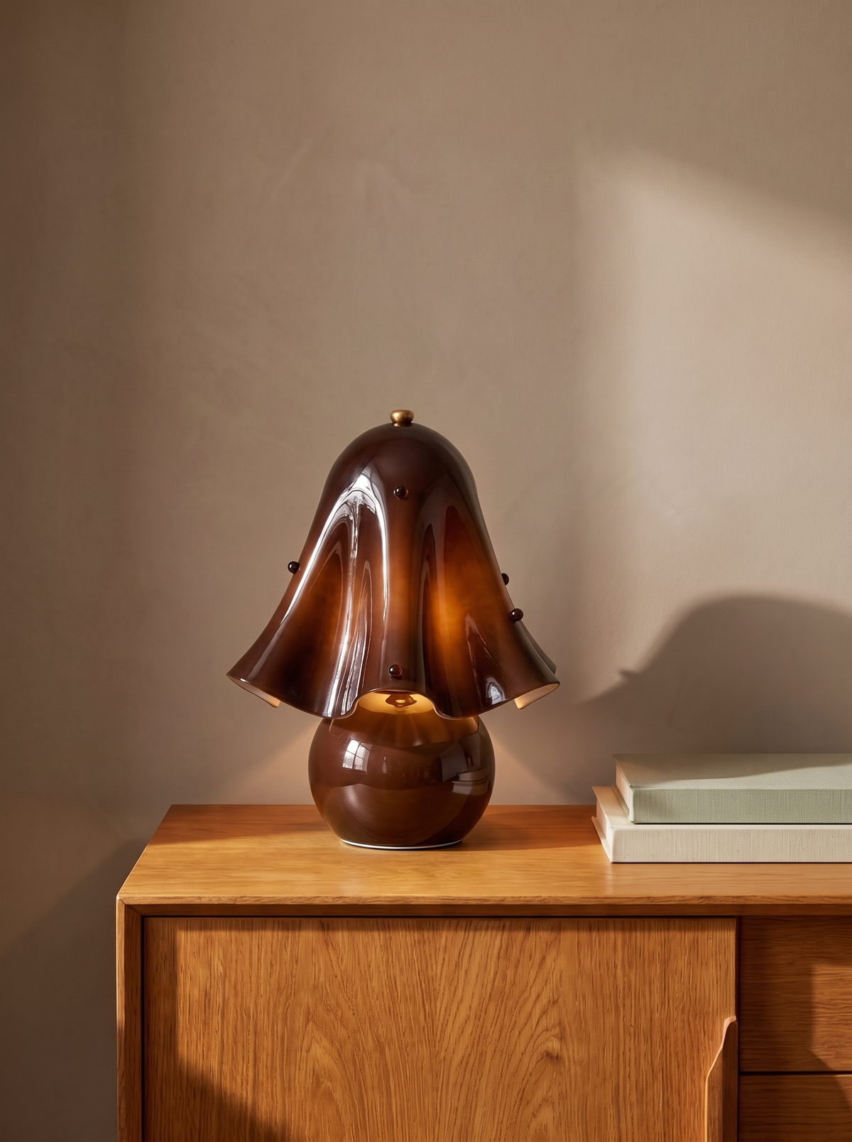 Petal brown glass flower table lamp on an oak console against a warm plaster wall