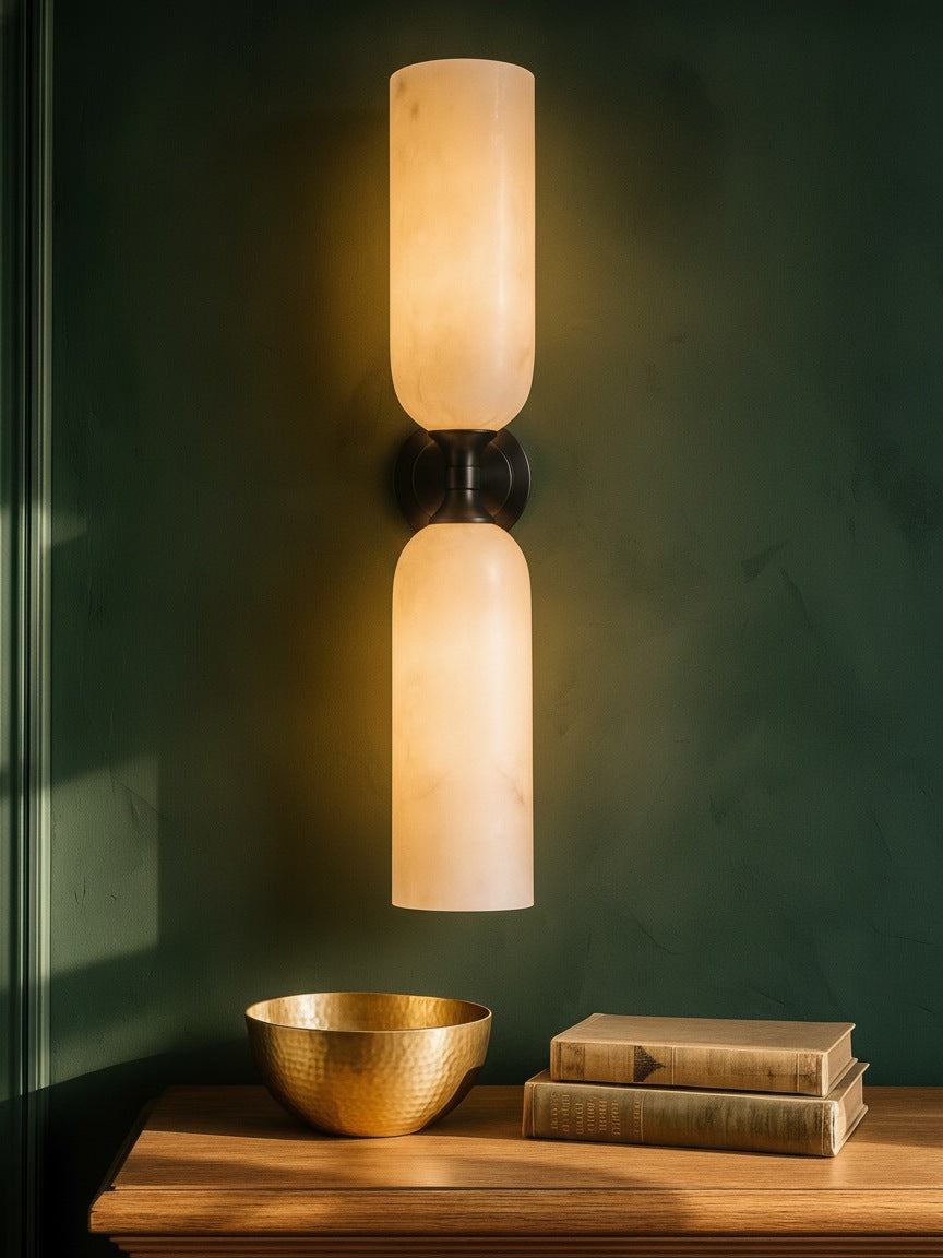 Nyx large up-and-down alabaster wall sconce in black on a forest-green plaster wall