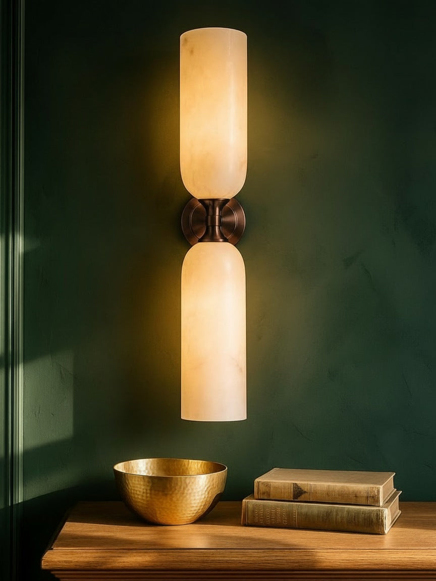 Nyx large up-and-down alabaster wall sconce in bronze on a forest-green plaster wall