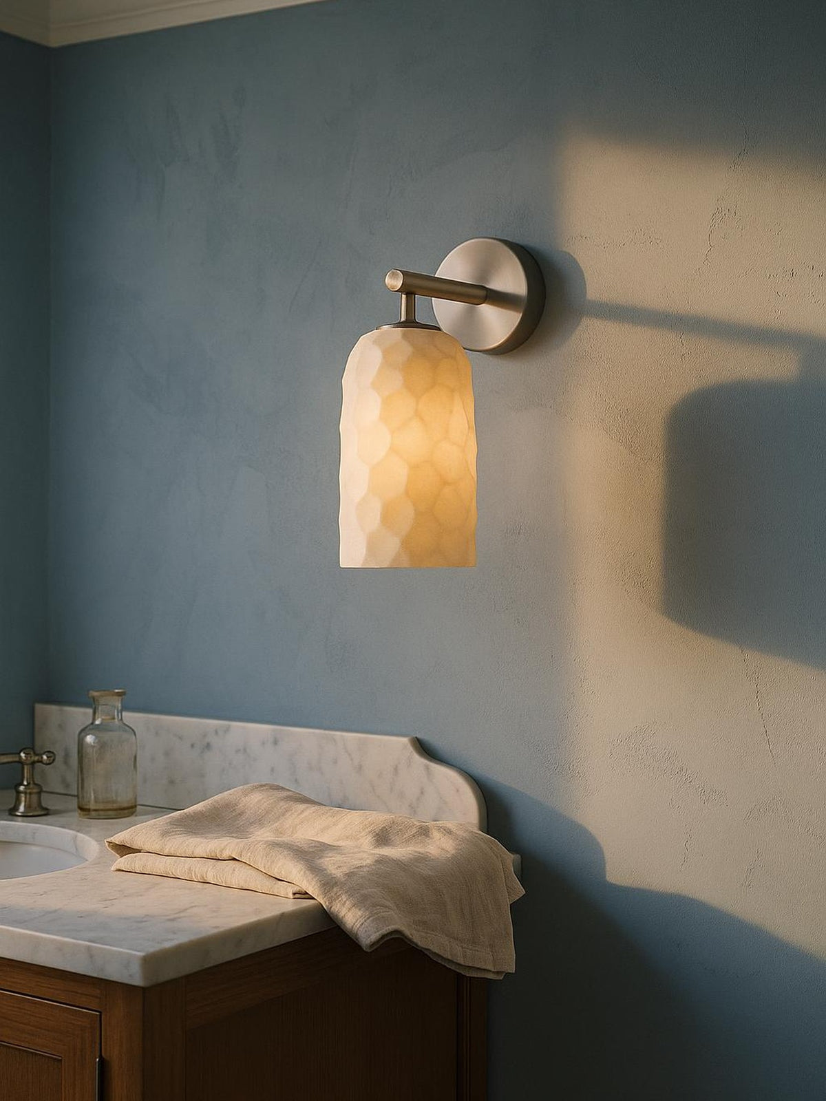 Pilar hand-faceted alabaster wall sconce in nickel on a powder-blue plaster wall