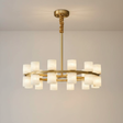 Enzo chandelier glowing warm on a plaster wall