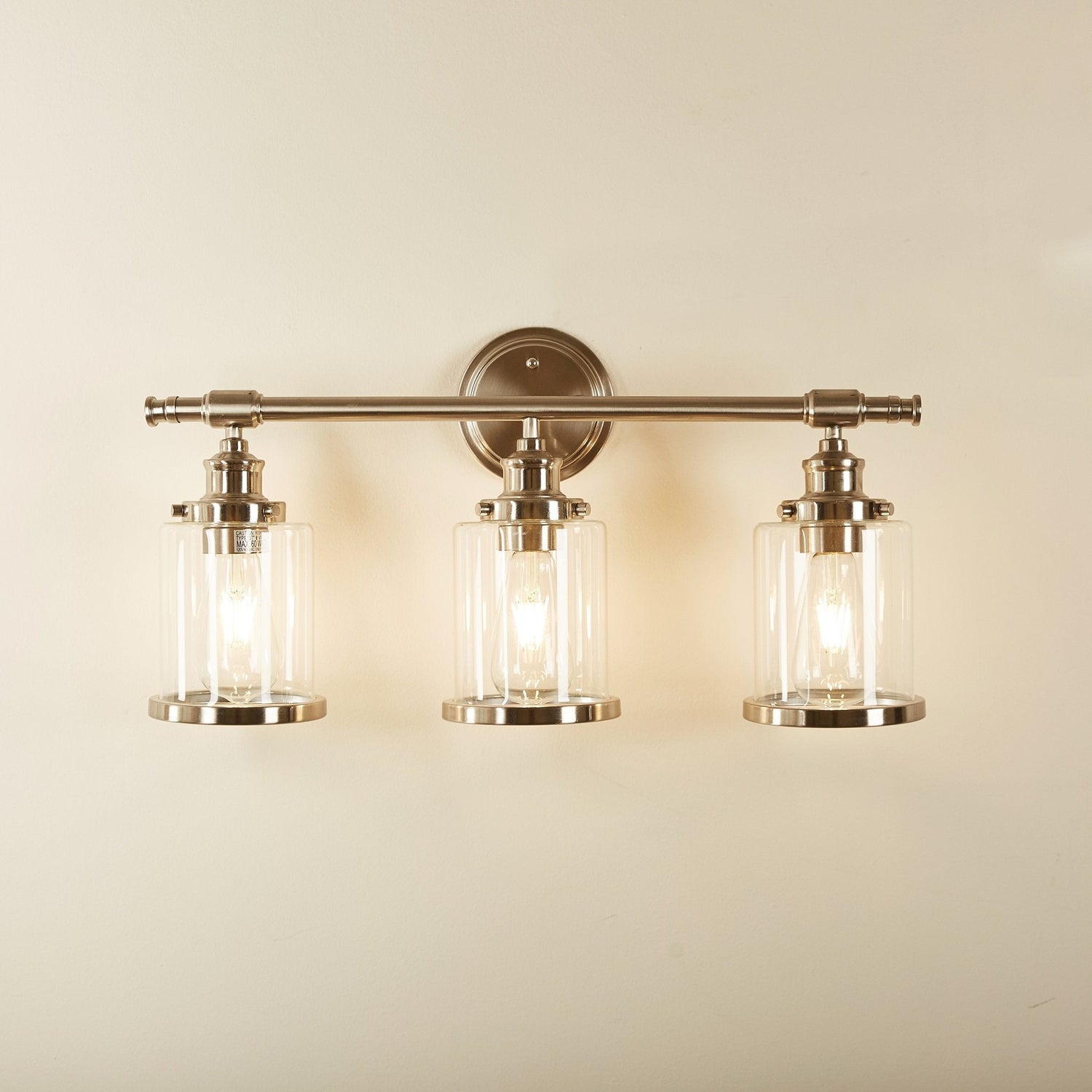 Greer vanity light lit on a warm bathroom wall, room scene