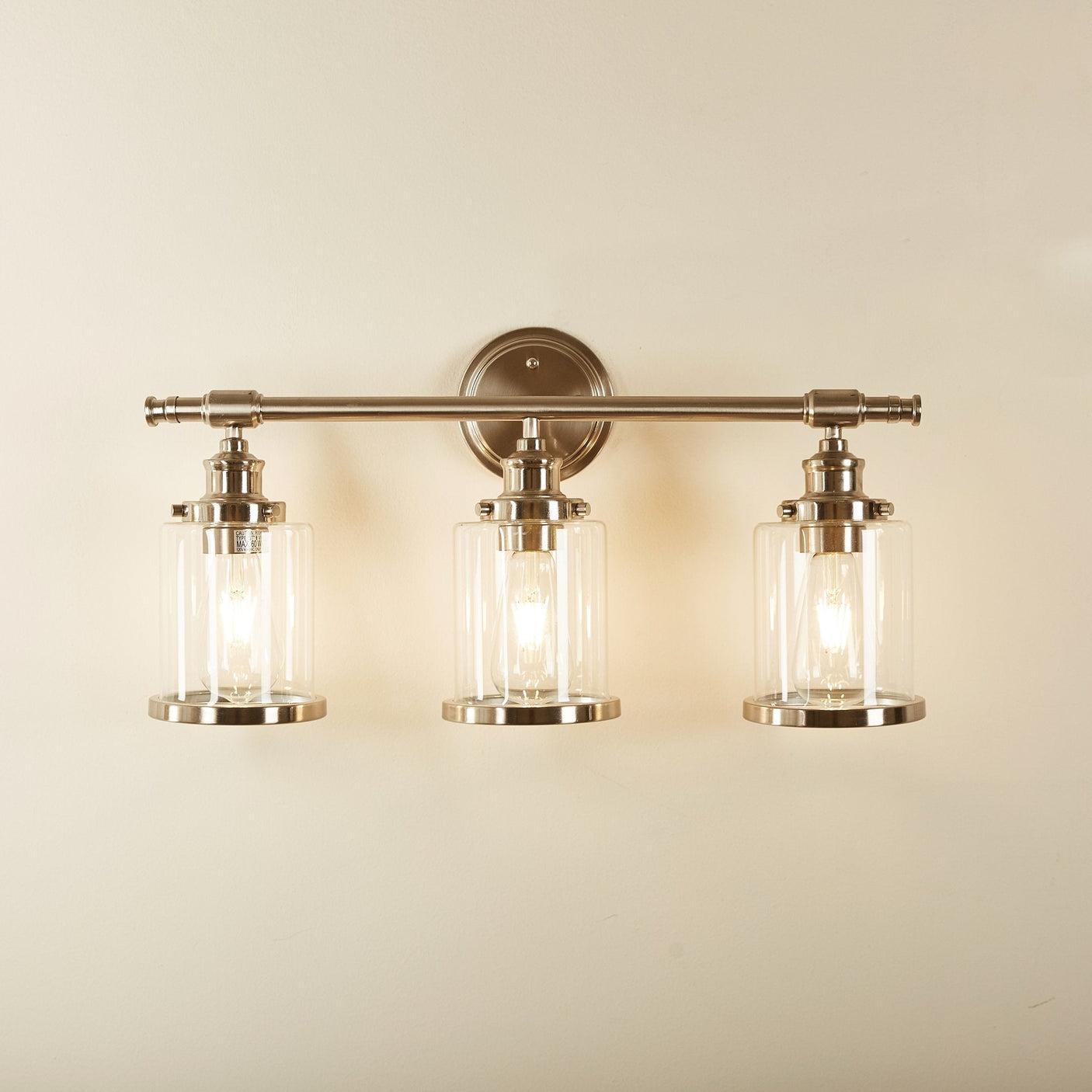 Greer vanity light lit on a warm bathroom wall, room scene