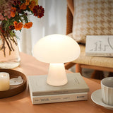 Ulla mushroom lamp glowing on a coffee table with flowers