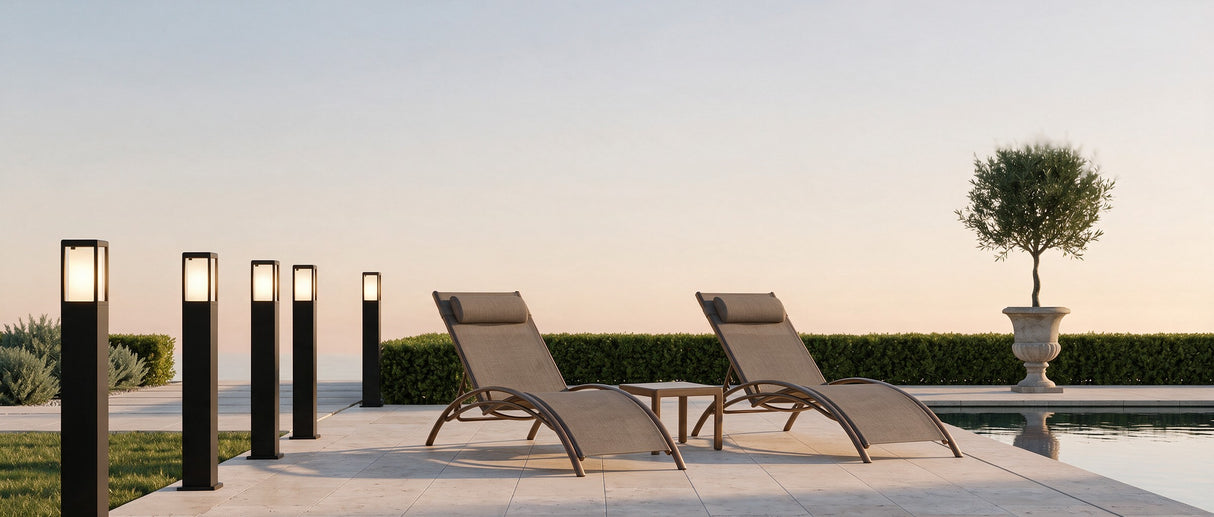 Cairn bollard lights along a travertine poolside walkway at dusk, lifestyle scene