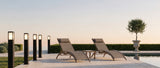 Cairn bollard lights along a travertine poolside walkway at dusk, lifestyle scene
