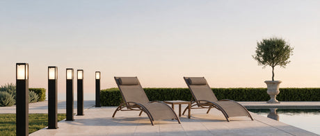 Cairn bollard lights along a travertine poolside walkway at dusk, lifestyle scene