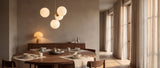 Gold globe chandelier over a walnut dining table with a wood table lamp at dusk — lifestyle