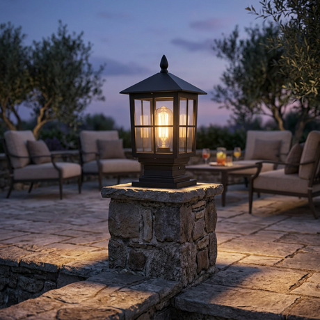 Gable coach lantern on a stone pillar at a patio terrace at dusk