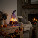Stained glass witch hat lamp glowing on a mantel with Halloween styling