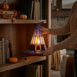 Hands placing the compact witch hat lamp on a bookshelf