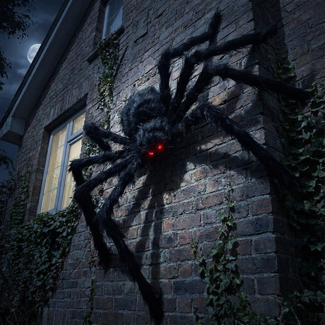 Black spider climbing a house wall at night