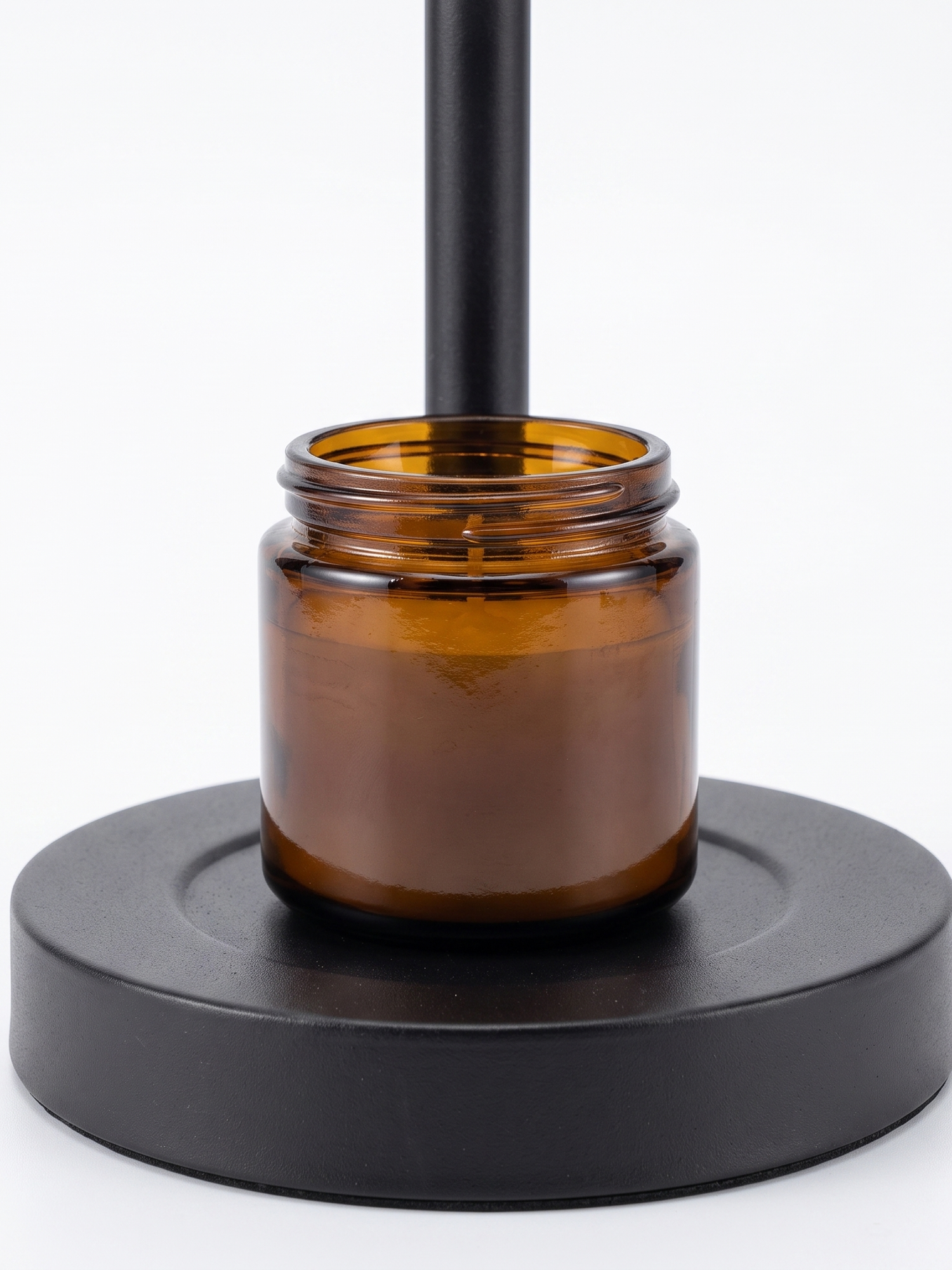 Ember candle warmer base with amber jar candle, close-up on white