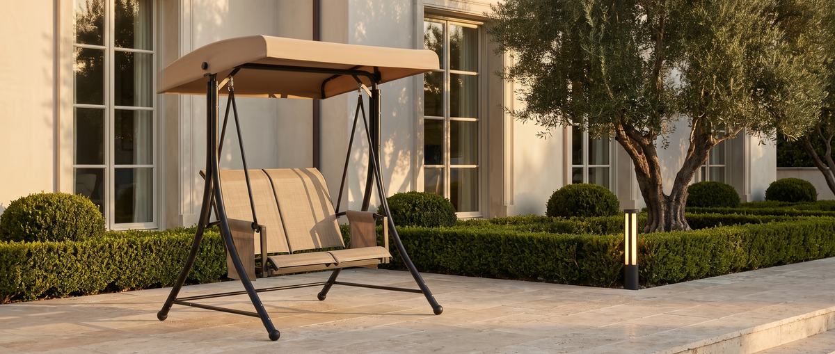 Barcelona swing on a travertine estate terrace at golden hour with a Tiixo bollard light — lifestyle