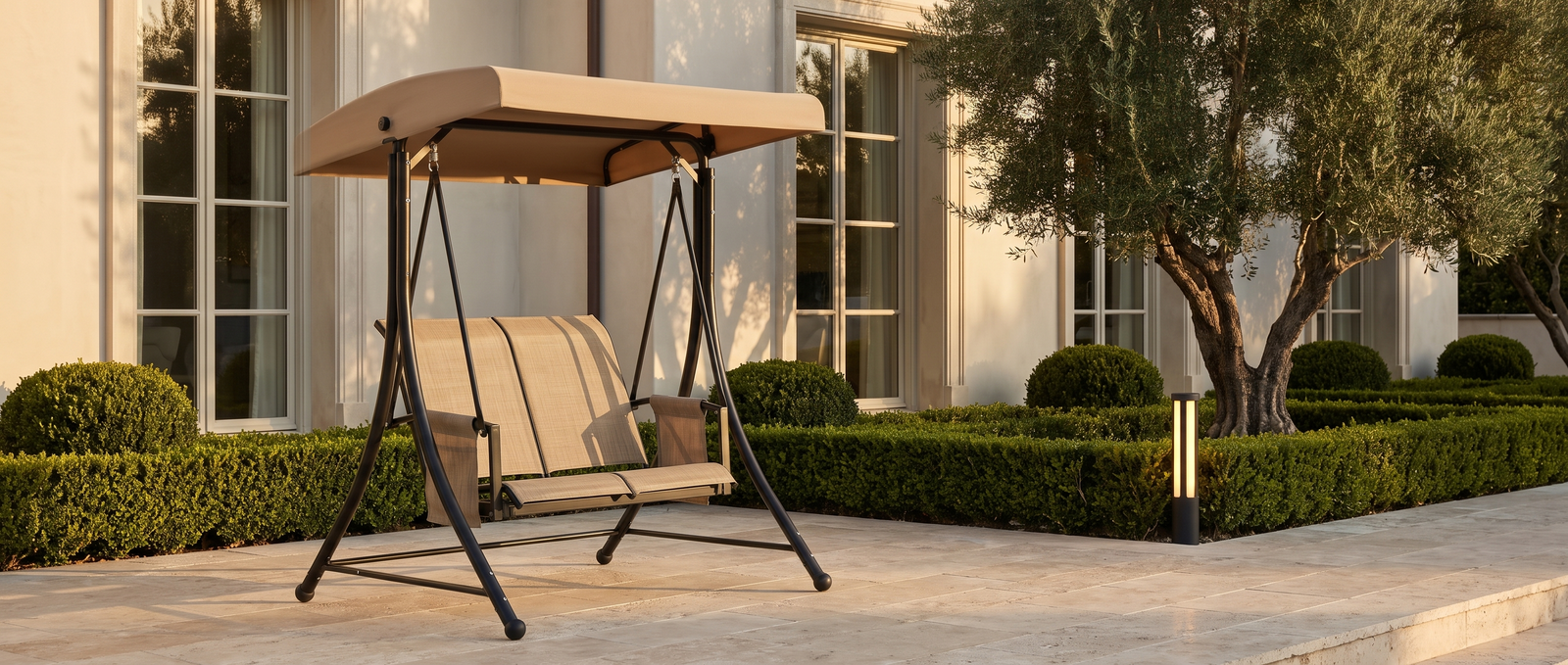 Barcelona swing on a travertine estate terrace at golden hour with a Tiixo bollard light — lifestyle