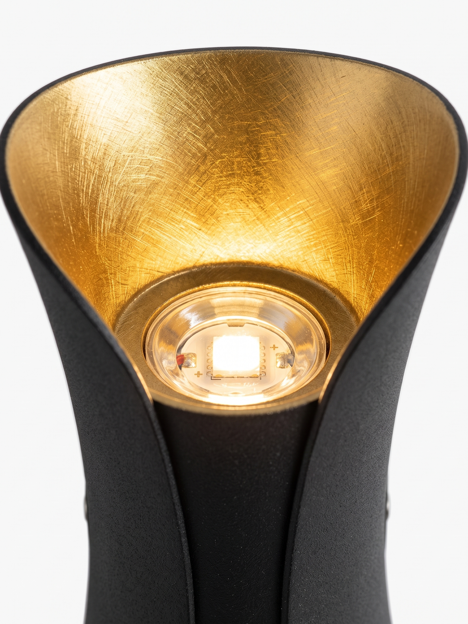 Brushed-gold reflector and LED emitter, close-up on white
