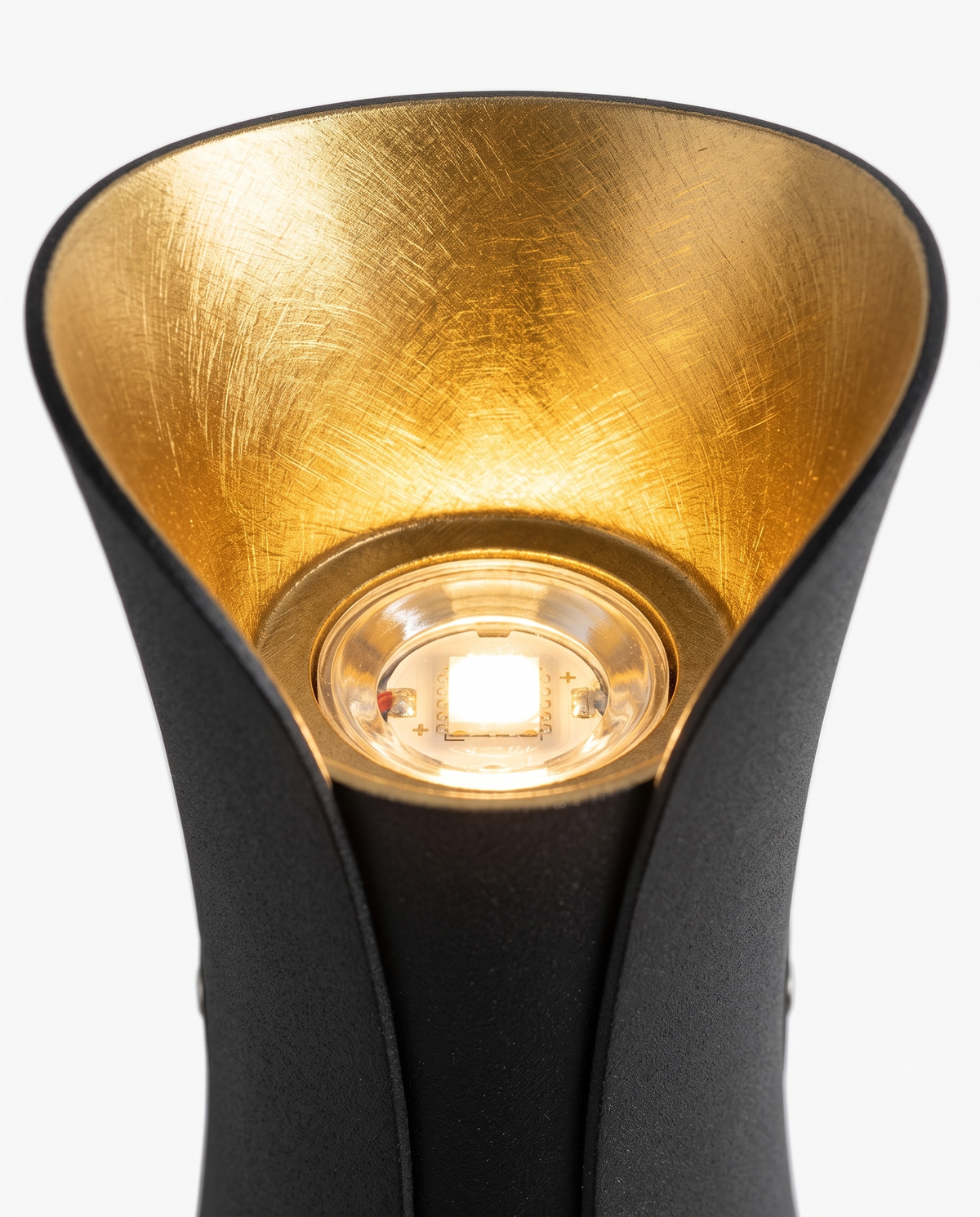 Brushed-gold reflector and LED emitter, close-up on white