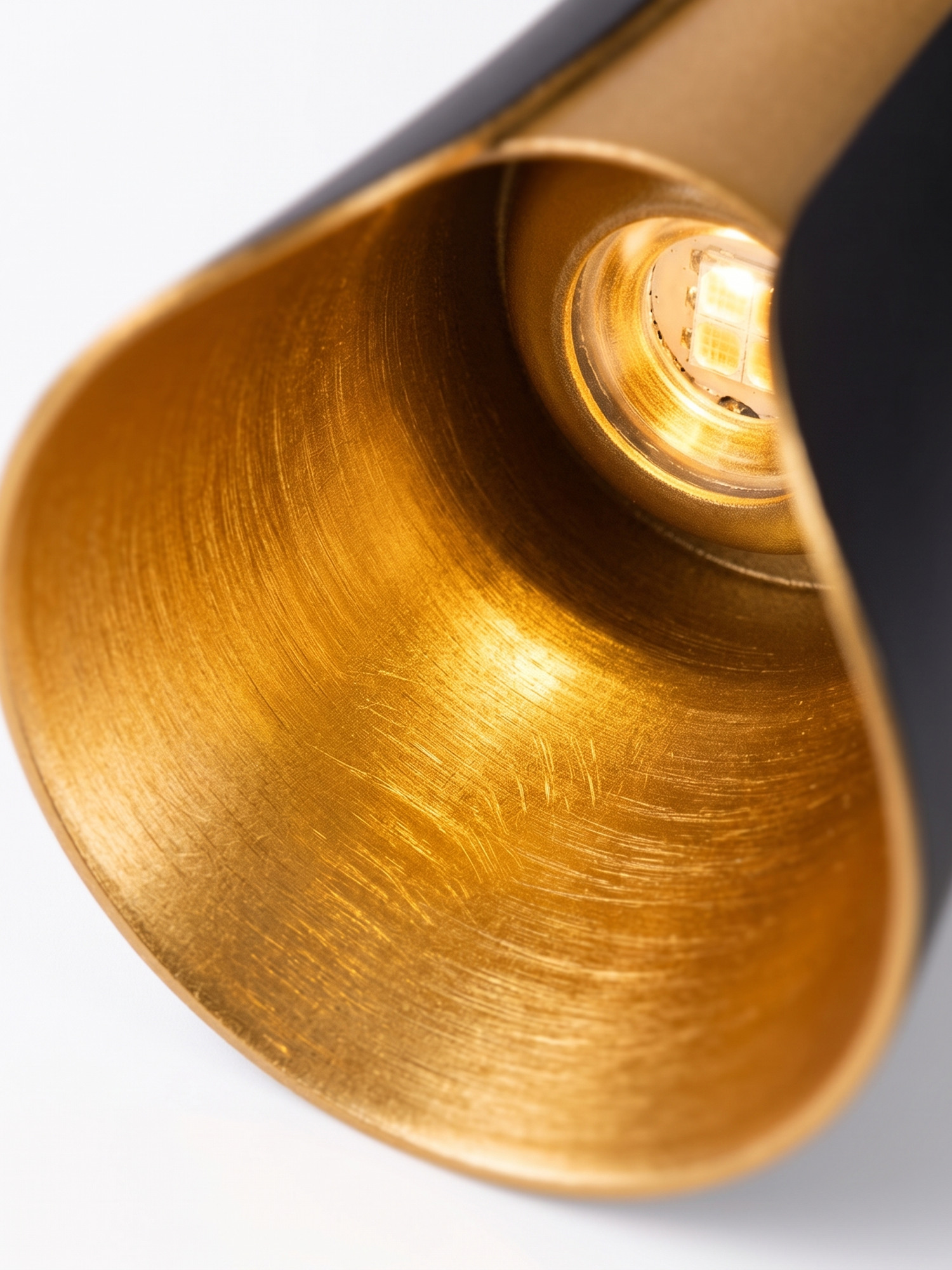 Brushed-gold reflector and warm LED, close-up on white