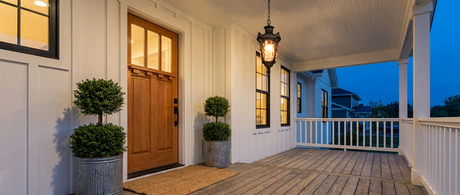 Noa lantern glowing on a classic white farmhouse covered porch at dusk lifestyle