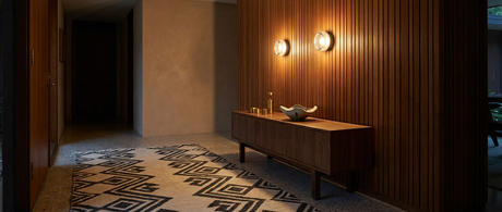 Corin sconces glowing on a teak-slat wall in a mid-century modern hallway lifestyle