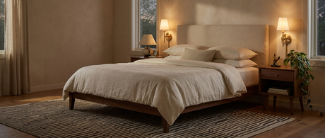 Pair of Veda brass sconces glowing beside a bed in a mid-century modern bedroom lifestyle