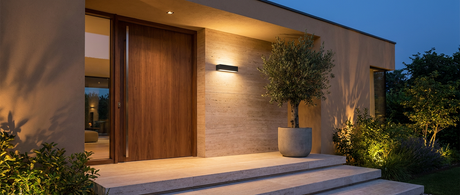 Aveline wall light casting a warm wash on a modern travertine entrance at dusk lifestyle