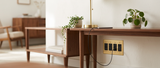 Voss brass outlet behind a walnut console in a mid-century room — lifestyle