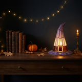 Solin stained glass witch-hat lamp glowing in a cozy autumn vignette