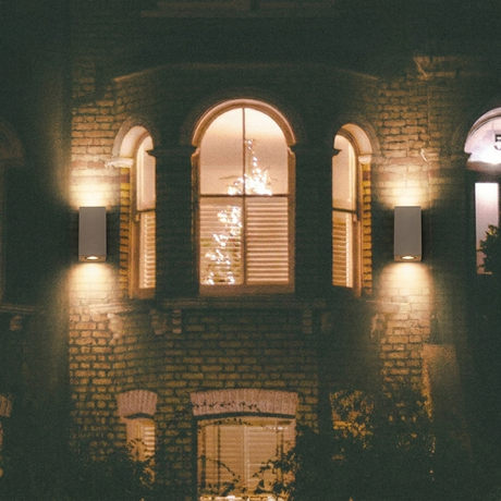 Ilse concrete up-down wall lights, pair on a brick townhouse at night