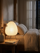 Akari rice paper lamp glowing on a nightstand in a Japandi bedroom