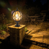 Lune globe pillar lantern on a stone pillar at a backyard flagstone patio at night