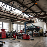 Isaac 120-inch HVLS industrial ceiling fan overhead in a busy auto mechanic shop with a car on the lift