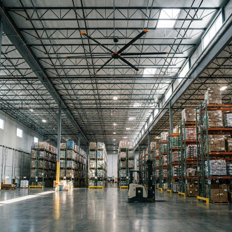 Isaac HVLS industrial ceiling fan mounted high in a warehouse with pallet racking and a forklift