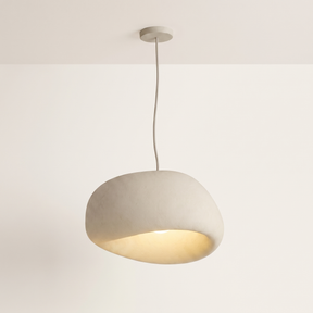 Saku pebble pendant light lit warm on a soft off-white studio background