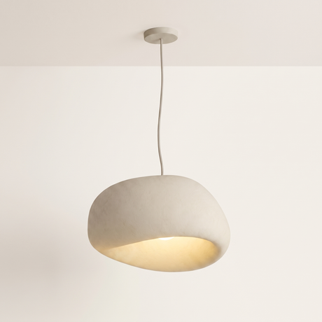 Saku pebble pendant light lit warm on a soft off-white studio background